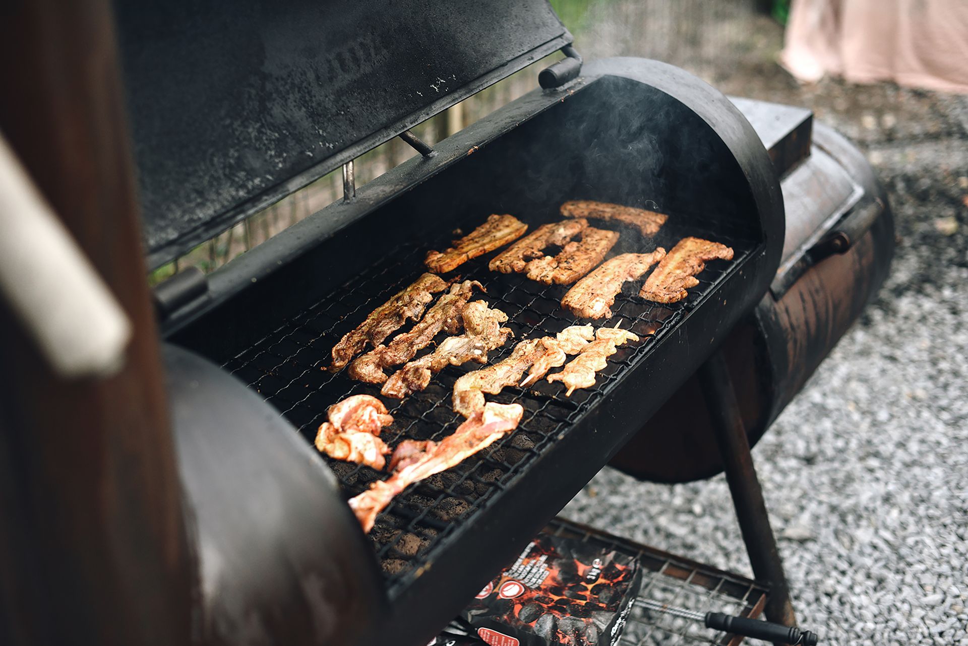 The offset smoker at work, smoke rolling off racks of meat