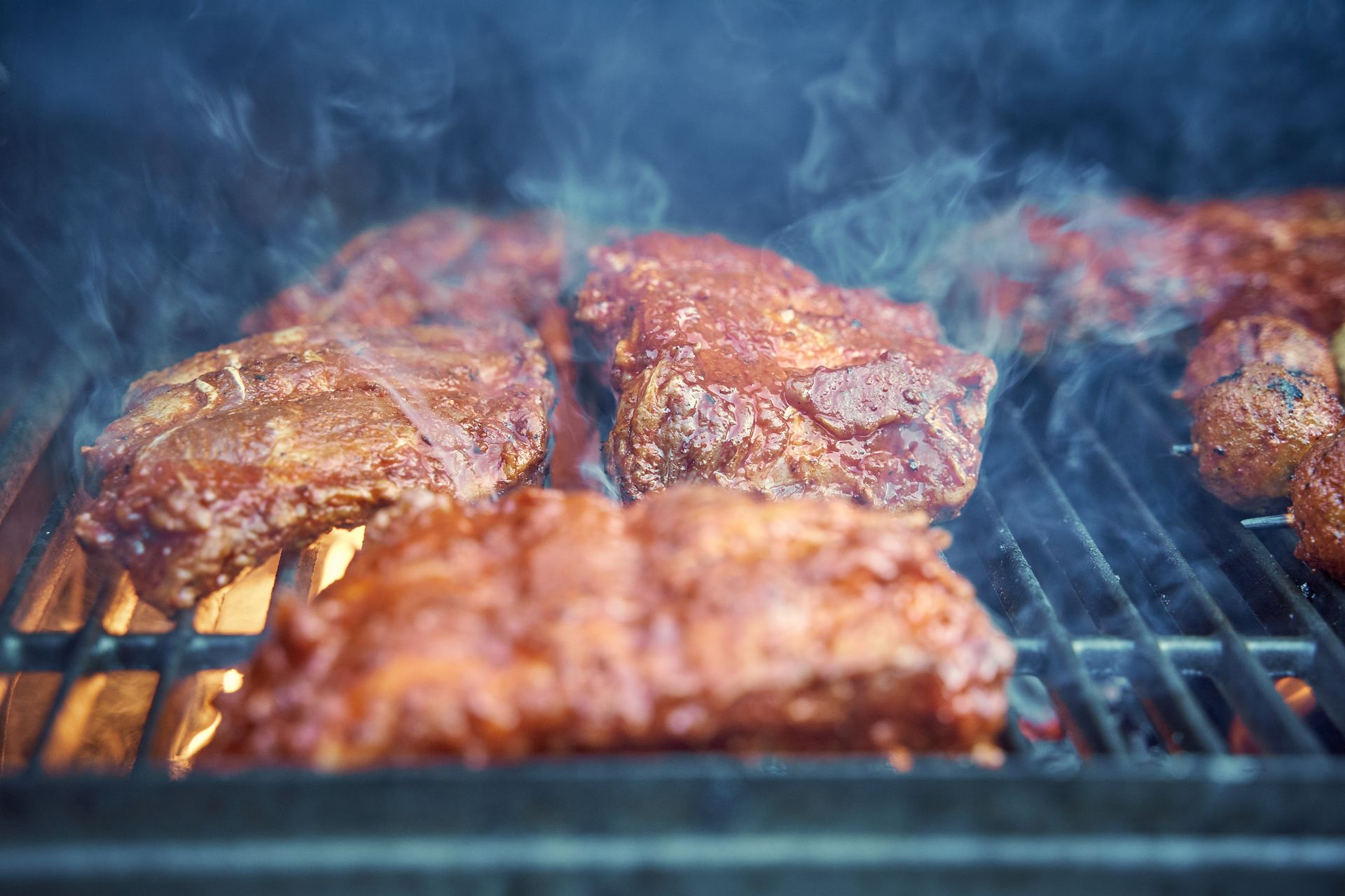Racks of St Louis ribs on the smoker, wreathed in smoke